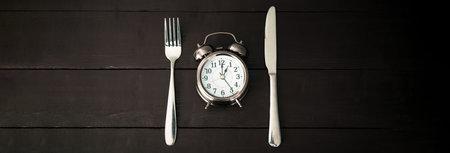 Alarm clock with fork and knife on the tableの写真素材