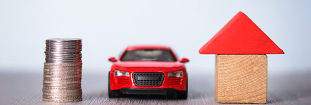 coins with car and house model on deskの写真素材