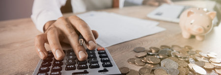 man hand calculator with coins on deskの写真素材