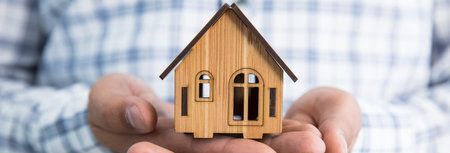 man hand holding wooden house modelの写真素材