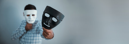 man face white with hand black mask on gray backgroundの写真素材