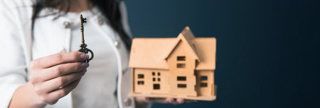 woman hand key with house model on dark backgroundの写真素材