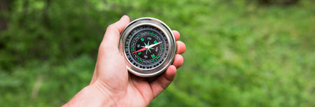 man hand holding comapss in green grass nature