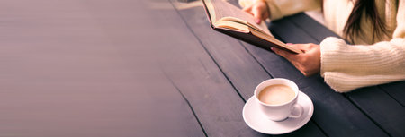 woman hand book with cup of coffee on table