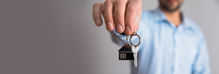 man hand holding house key on gray backgroundの写真素材