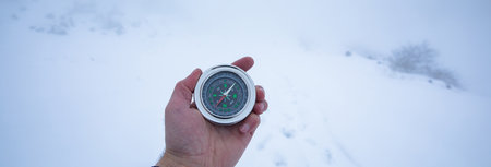 man hand compass in snowy mountain backgroundの写真素材