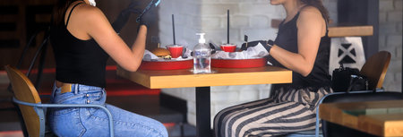 two woman eating burger sitting in the cafeの写真素材
