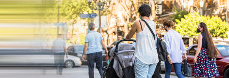Woman with stroller walking along the street.