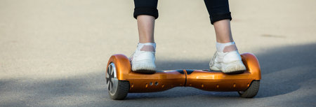 Feet of girl riding on electric mini gyro scooter board in parkの写真素材