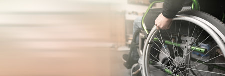 Close-up of male hand on wheel of wheelchairの写真素材