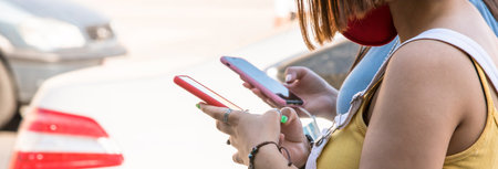 womans holding phones are walking in street
