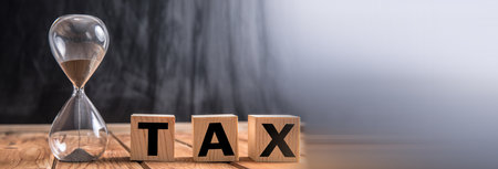 Tax word on wooden cubes with hourglass.