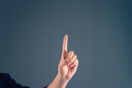 Woman number 1 hand gesture, gray backgroundの写真素材