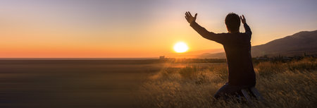 man with hands raised in the sunset concept for religion