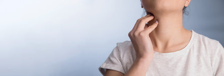 Sore throat. Woman holding hands on her throat.