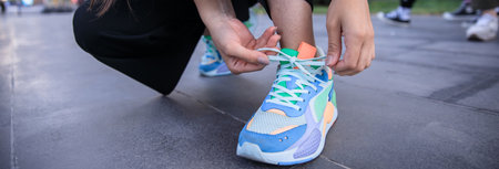 woman in sports clothing tying shoelace in street