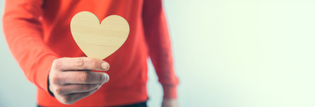 young man holding wooden heartの写真素材