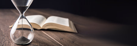 hourgass with book on the wooden backgroundの写真素材