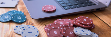 poker chips on computer laptop on the tableの写真素材