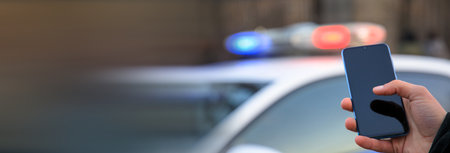 man holding phone with police car lightの写真素材
