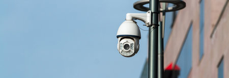 Security camera mounted on pole against blue sky.