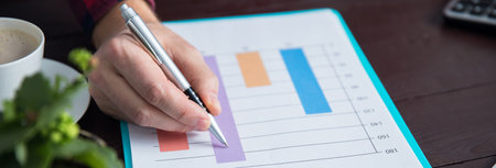 Business man hand holding pen working with graph