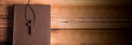 wooden cross with open Bible on bokeh background