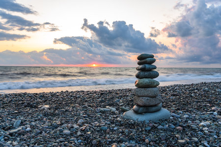 Balance on a pebble on the beach at sunsetの写真素材