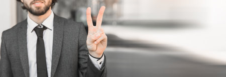 Portrait of a successful man showing victory sign in streetの写真素材