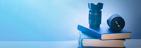 Objective of a camera and a stack of books on a wooden boardの写真素材