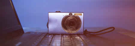Computer keyboard and camera lie on table.の写真素材