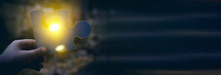 A hand holding a jigsaw pieceの写真素材