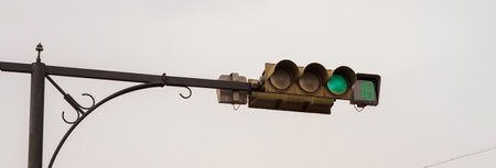Green traffic light against gray sky