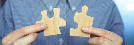 Closeup of businessman wanting to put two pieces of puzzle together.の写真素材