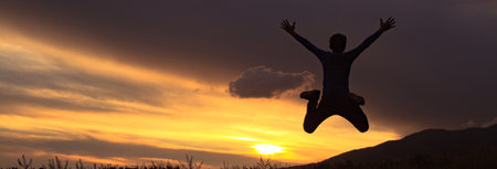 Silhouette of a boy jumping at sunset.の写真素材