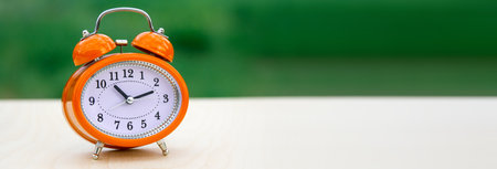 Orange alarm clock on a green and white background.