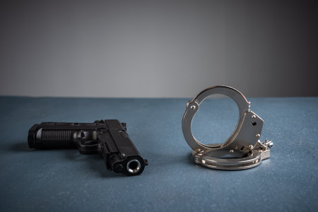 Gun and handcuffs on blue background, stock photo, criminal conceptの写真素材
