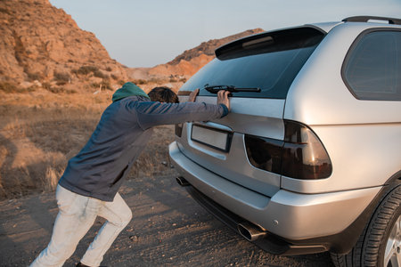 the man was pushing the broken down car on the road. stock photo