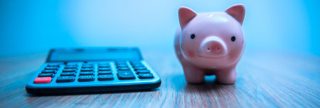 Calculator and piggy bank on a wooden desk.の写真素材