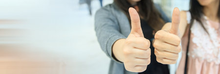 A closeup of two young girls showing their thumbs up.