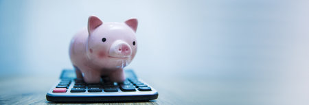 Pink piggy bank and calculatpr on a wooden table, plain bakground.の写真素材