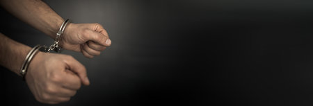 Man hand handcuffs on dark backgroundの写真素材