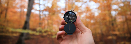 A beautiful male hand holds a magnetic compass in the coniferous autumn forest.の写真素材