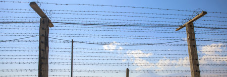 Barbed wire fence on blue sky background.