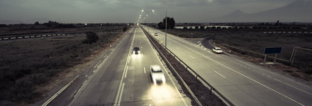 Countryside highway at night with several cars.