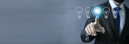 Businessman pressing button with bulb on virtual screensの写真素材