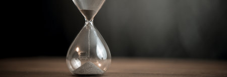 Hourglass on the wooden table background
