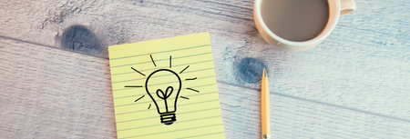 The drawing of a bulb on paper with coffee on tableの写真素材