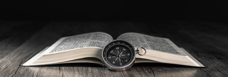 Book and compass on the table. Concept direction worldview
