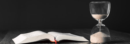 Hourglass and open book on the table